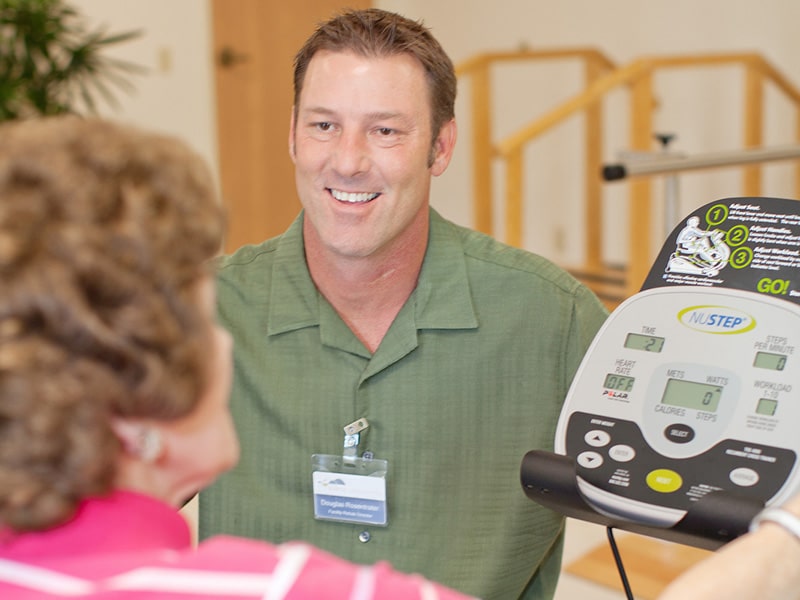 a rehab therapists assisting an elderly woman in the rehab gym
