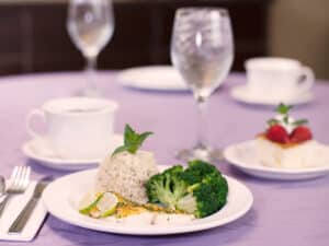 the dining room with a gourmet meal on a dinner plate with linen tablecloths at Bishop Care Center